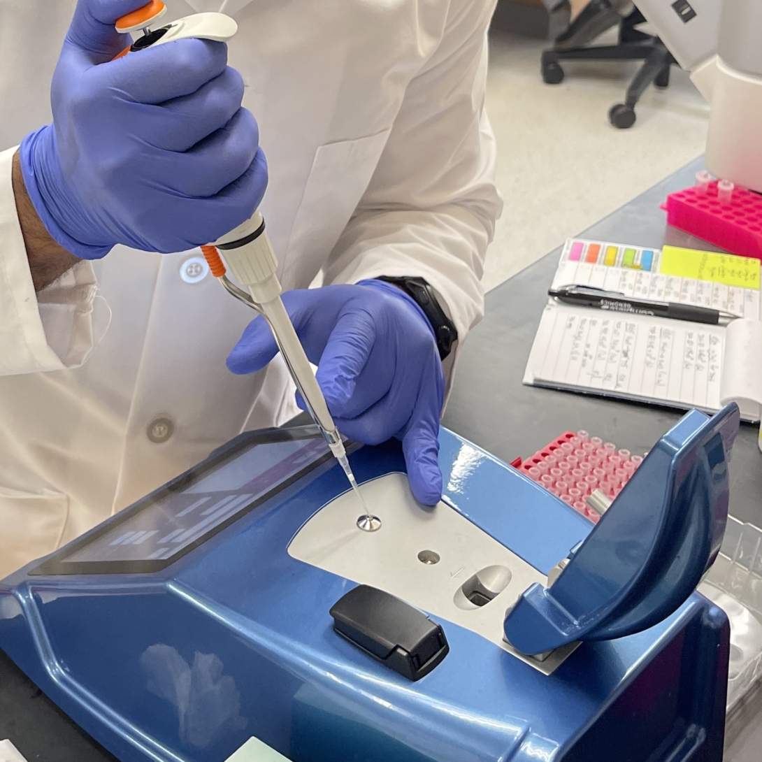 lab member using a micropipette to load a sample onto a spectrophotometer