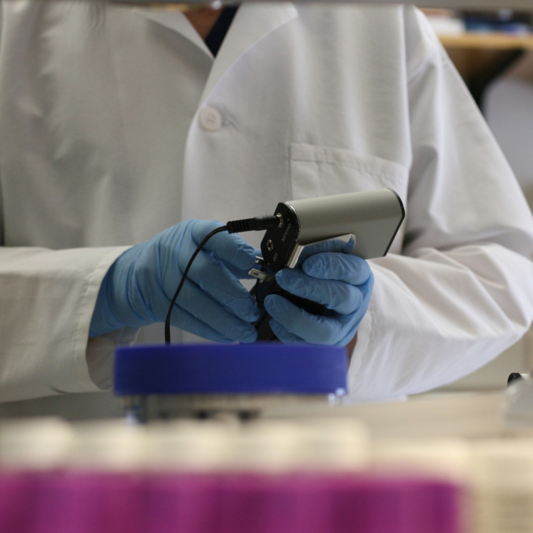 lab technician holding a small handheld electronic instrument