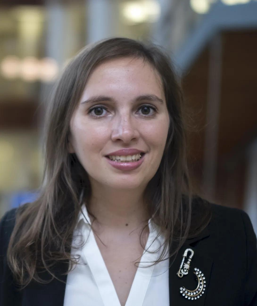 Natalia Cantet smiling in a black blazer and white blouse, wearing a decorative brooch.