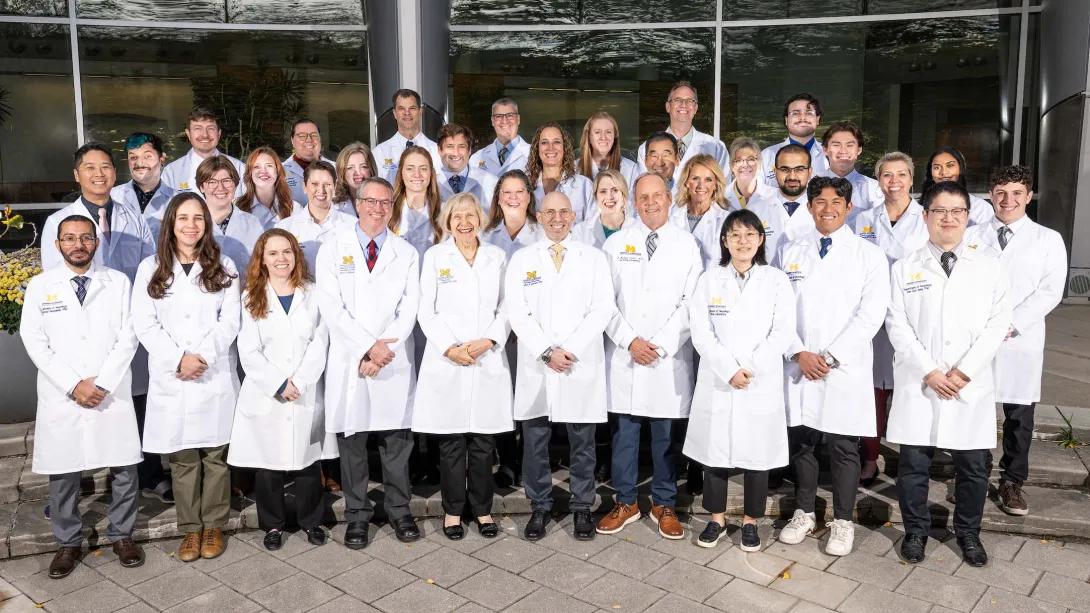 A group shot of the 2025 NeuroNetwork for Emerging Therapies lab in lab coats standing outside of the BSRB