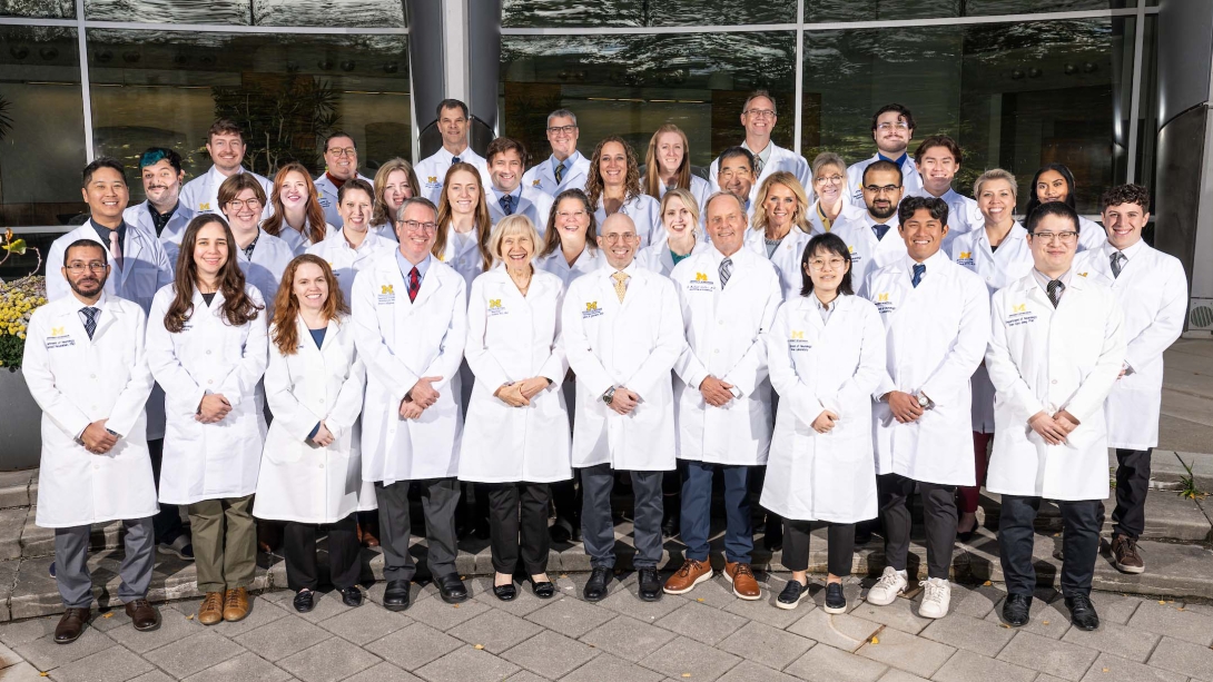 A group shot of the 2025 NeuroNetwork for Emerging Therapies lab in lab coats standing outside of the BSRB
