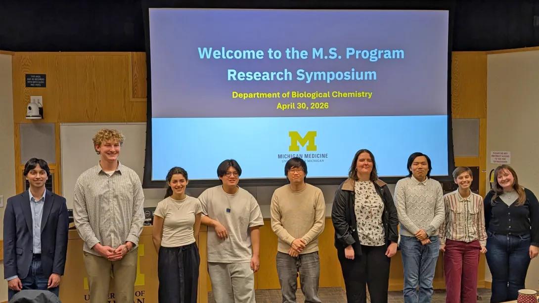 Group photo of students in front of symposium presentation screen
