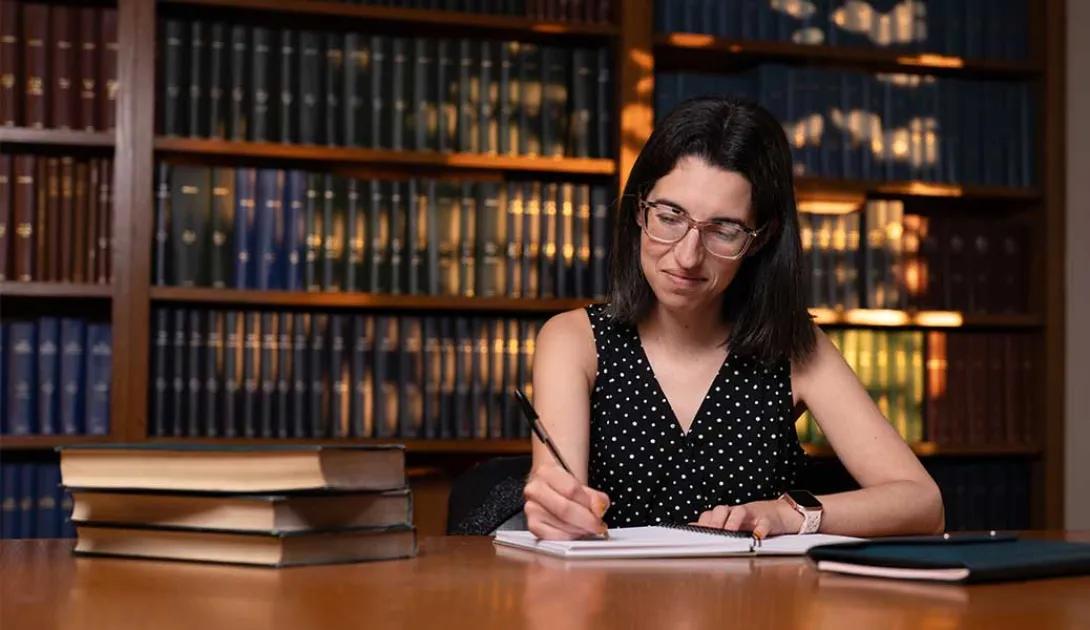 Dr. Victoria Wytiaz writes at a desk in the library