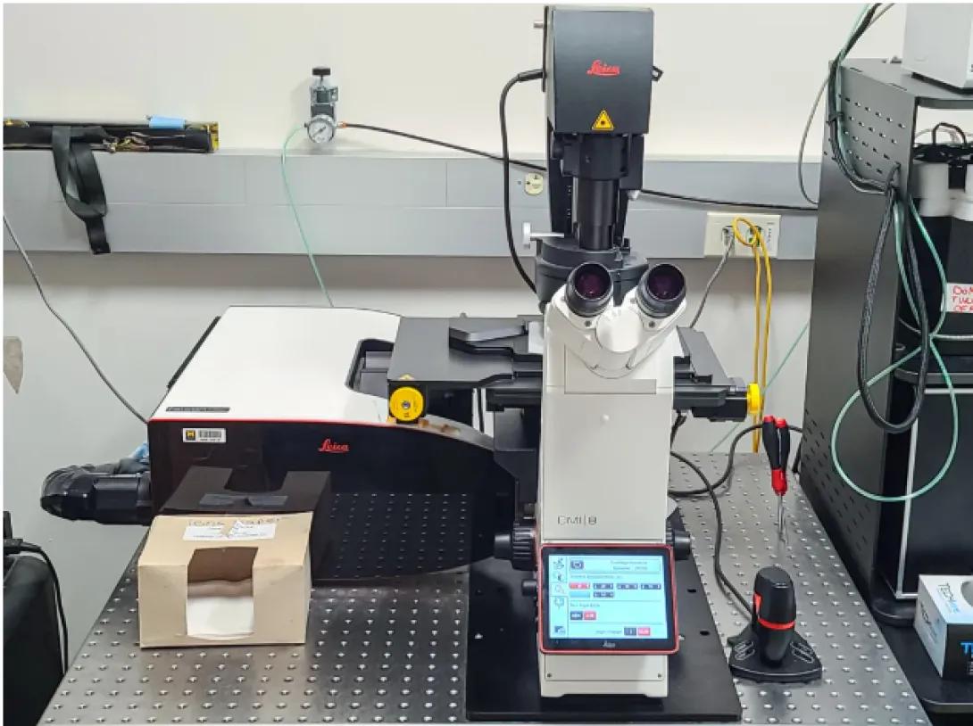 High-resolution laboratory microscope with digital controls and imaging equipment on a research lab workbench.
