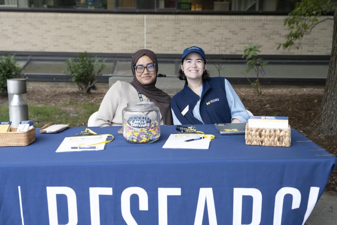 two people posing for a photo at a tabling event outdoors