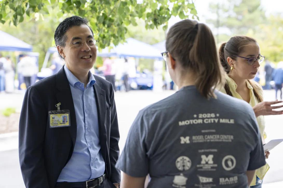 candid picture of people talking and smiling at a tabling event outdoors
