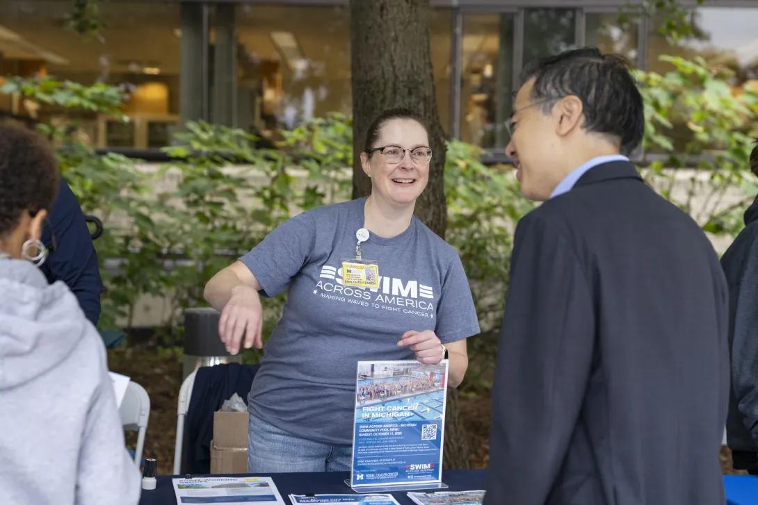 candid picture of people talking and smiling at a tabling event outdoors