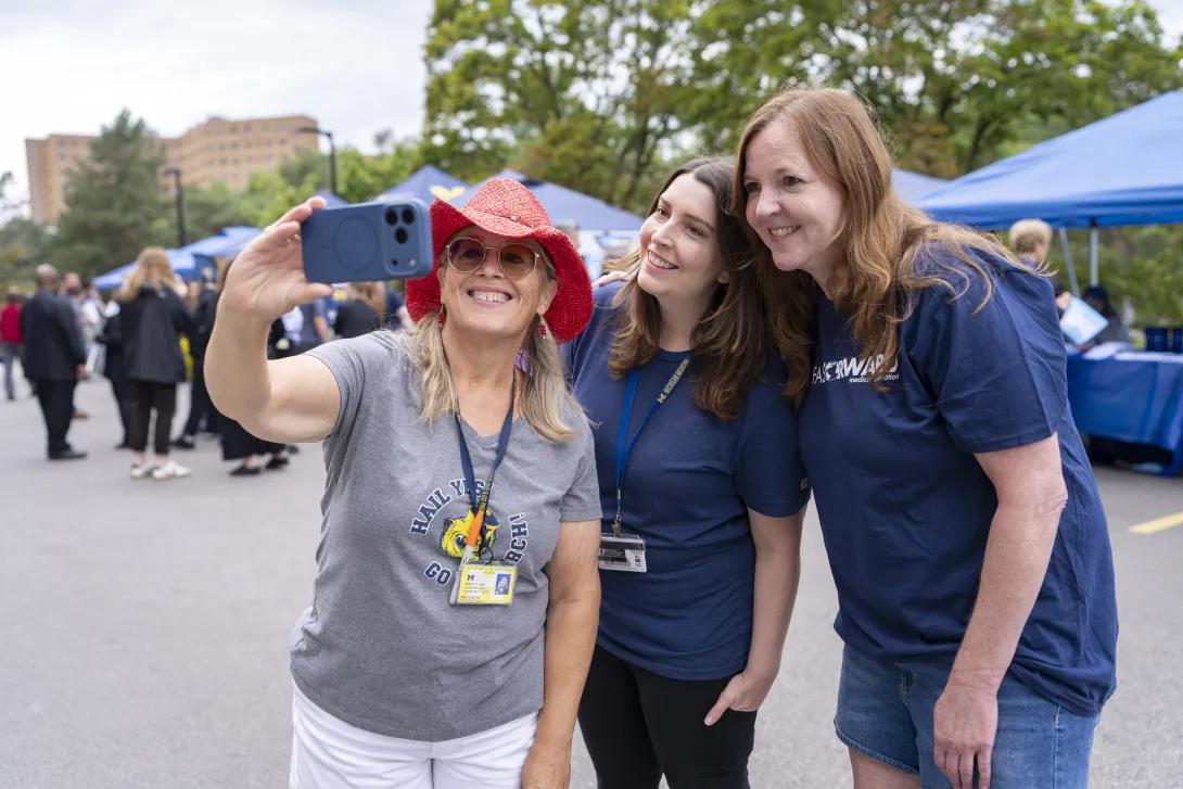candid picture of people taking a selfie at a tabling event outdoors