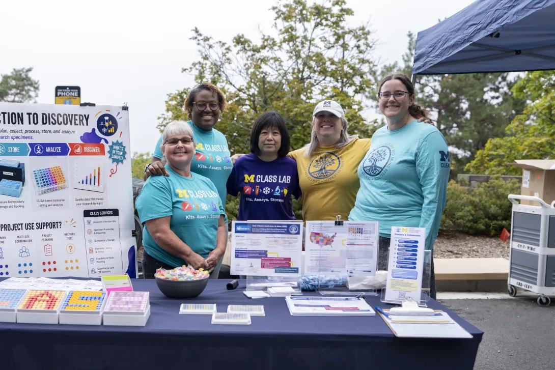 group of people posing for a photo at a tabling event outdoors