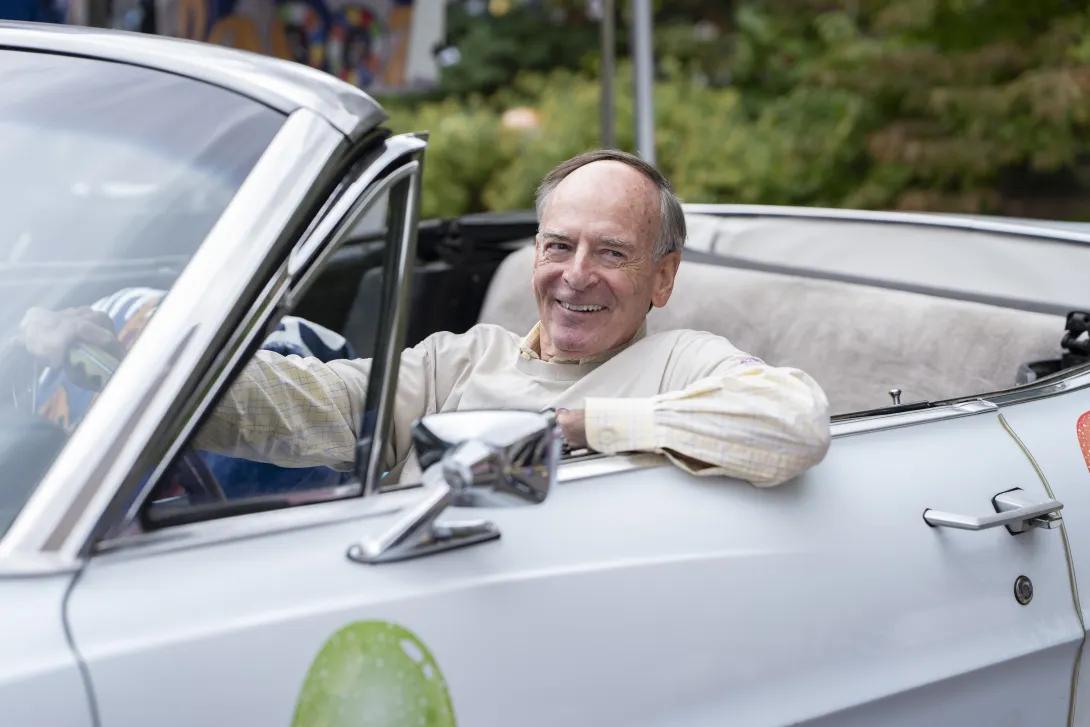 man smiling, driving a classic car