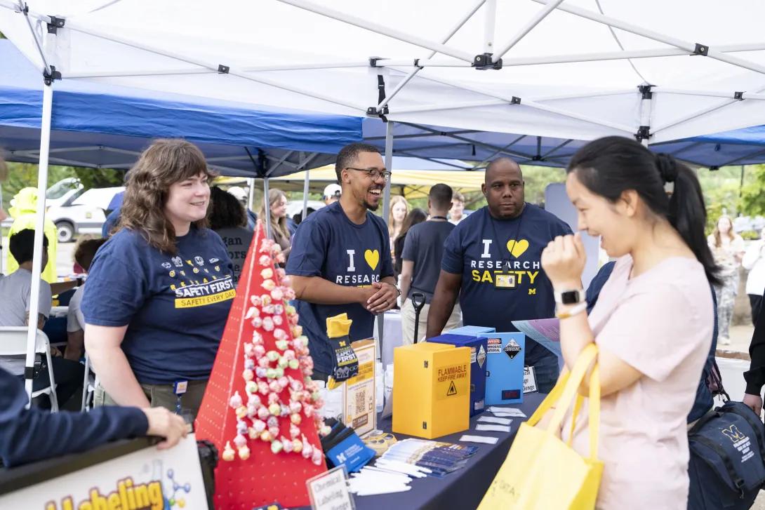 candid picture of people talking and smiling at a tabling event outdoors