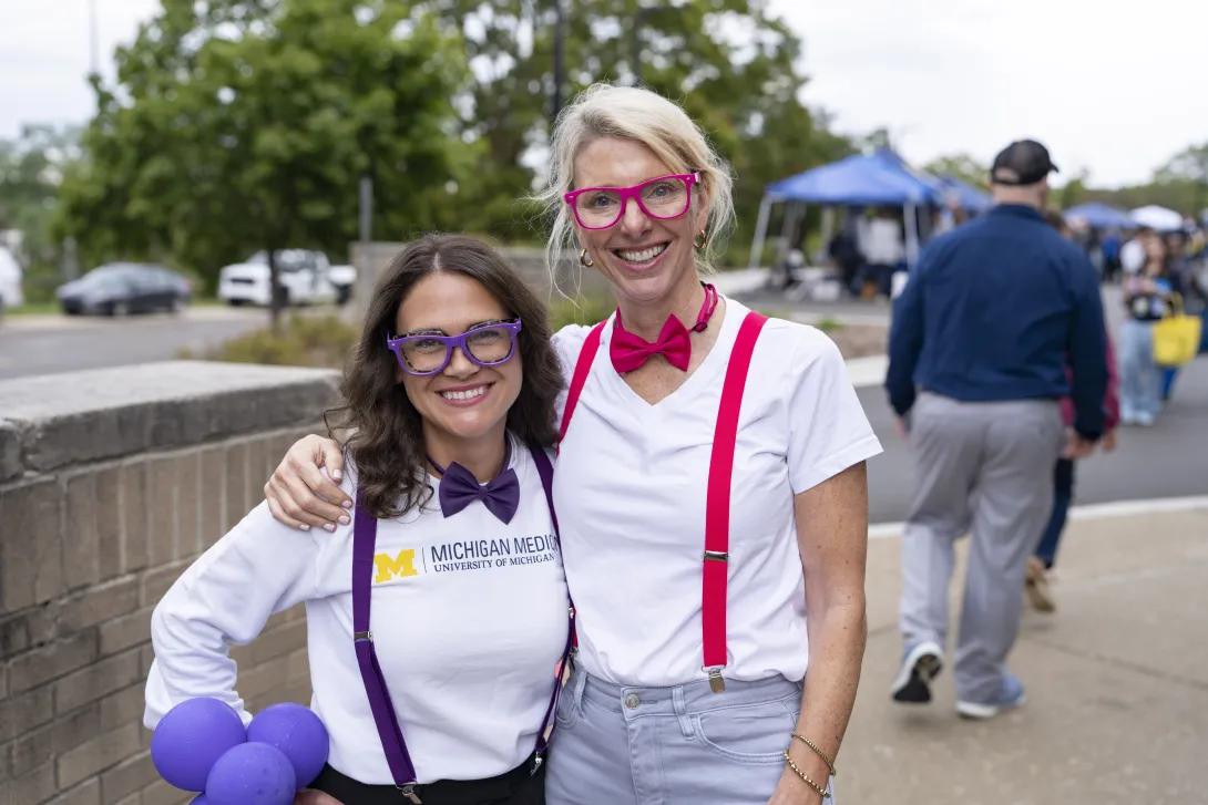 two people wearing "nerd" costumes posing for a photo at a tabling event outdoors