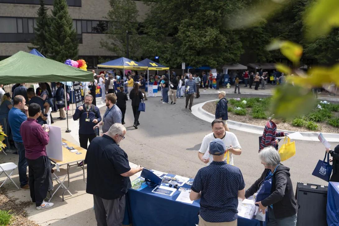 distant picture of people talking and smiling at a tabling event outdoors