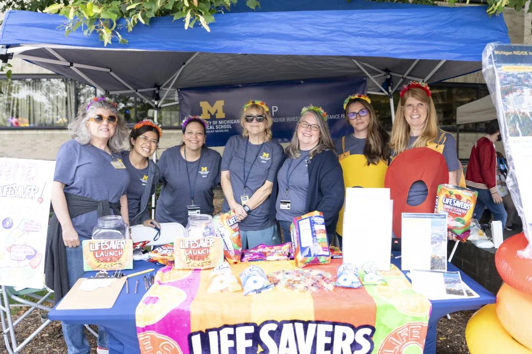 group of people posing for a photo at a tabling event outdoors