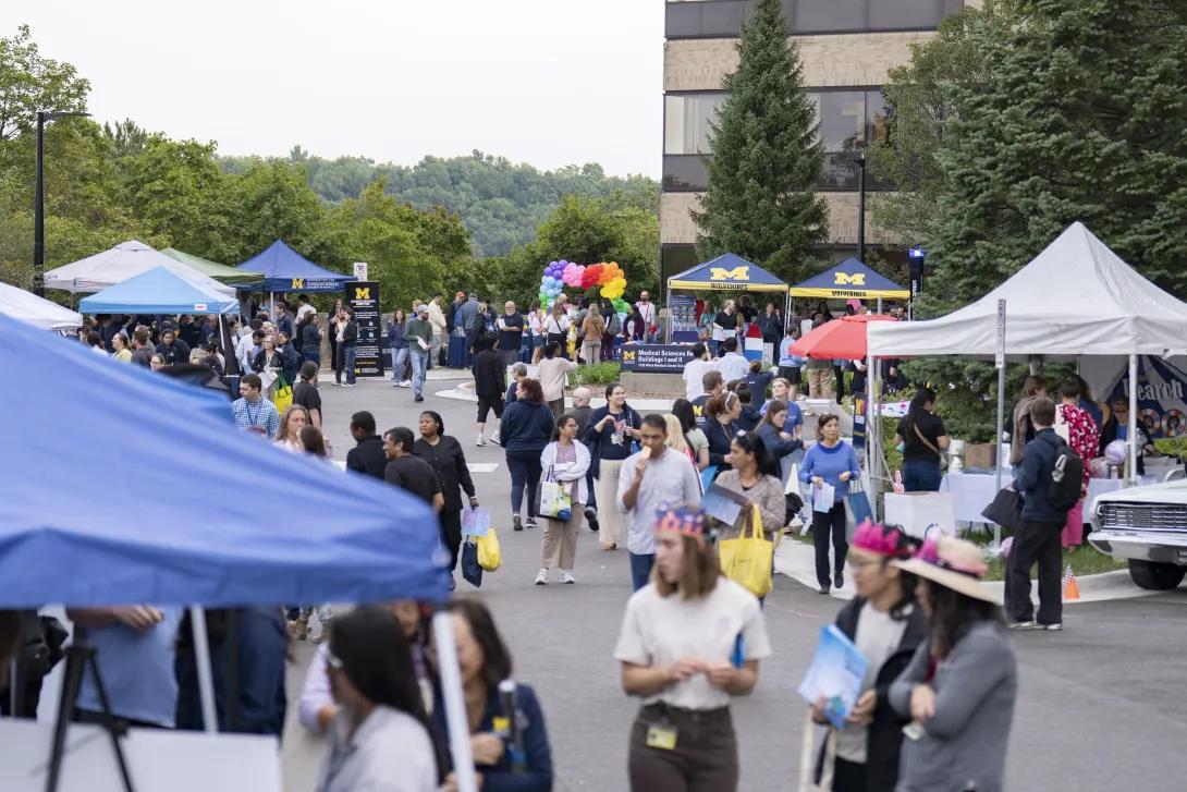 distant picture of people talking and smiling at a tabling event outdoors