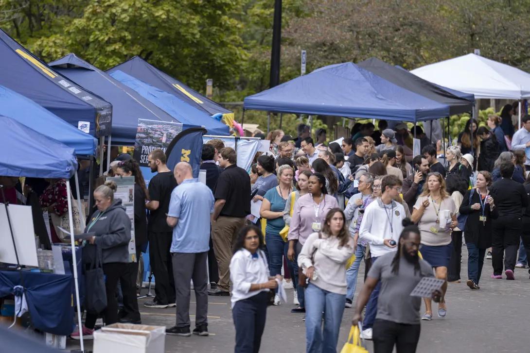 distant picture of people talking and smiling at a tabling event outdoors