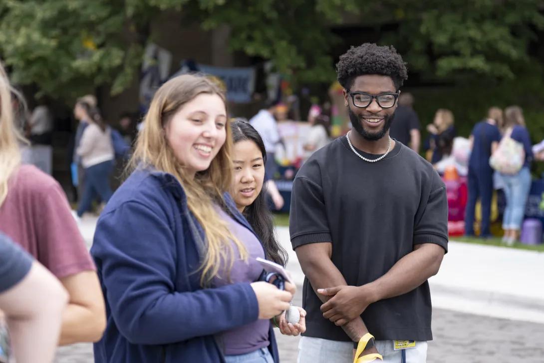 candid picture of people talking and smiling at a tabling event outdoors