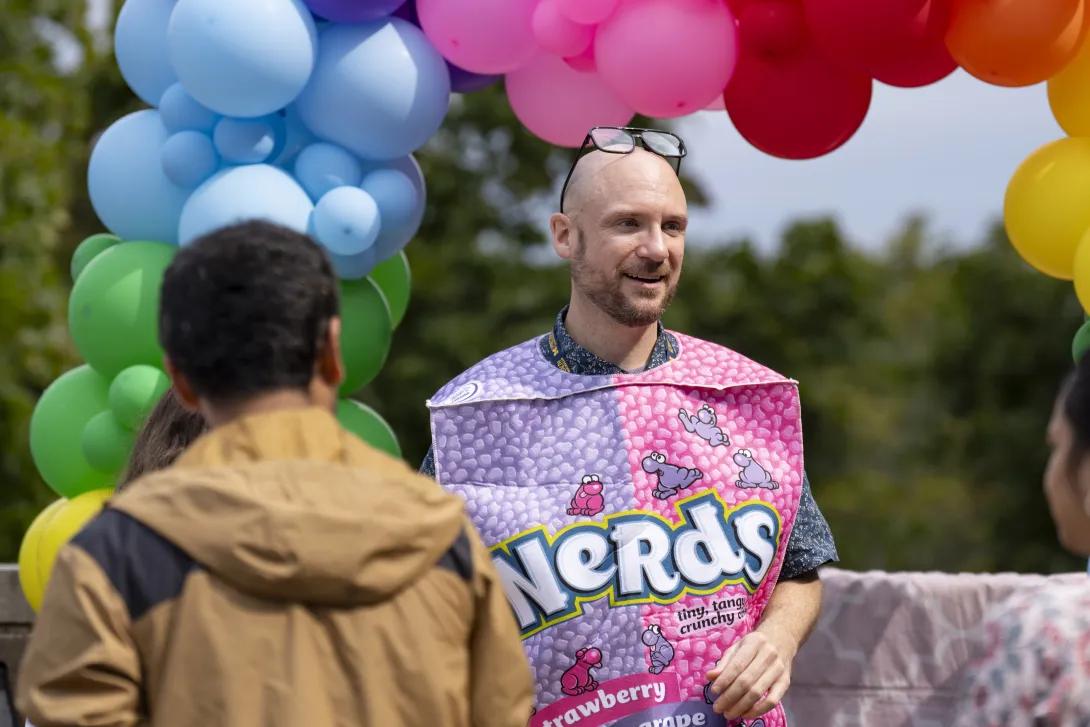 man wearing a costume and smiling at a tabling event outdoors