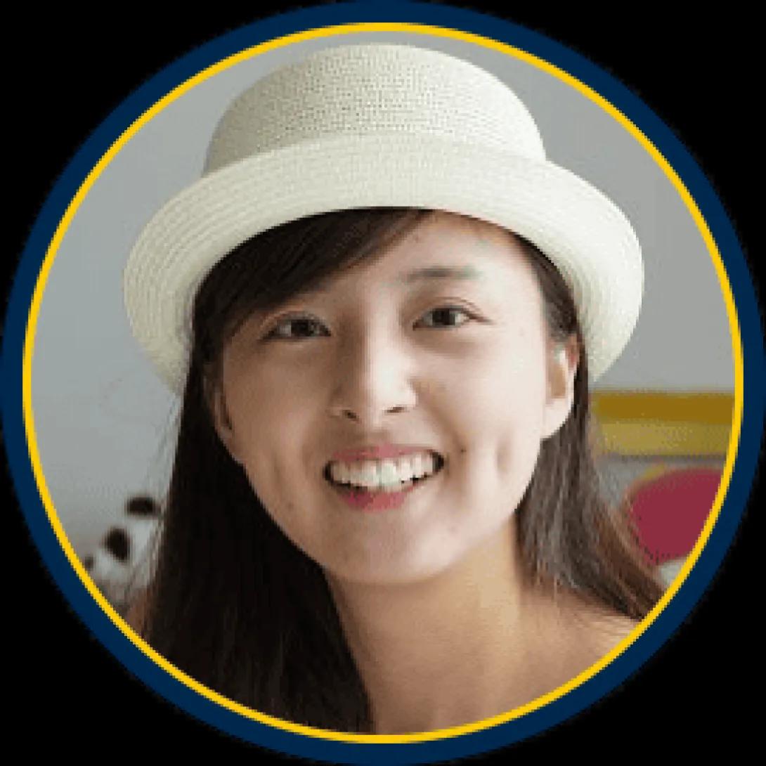 Joyce Wang: woman with dark brown hair and a white hat smiling